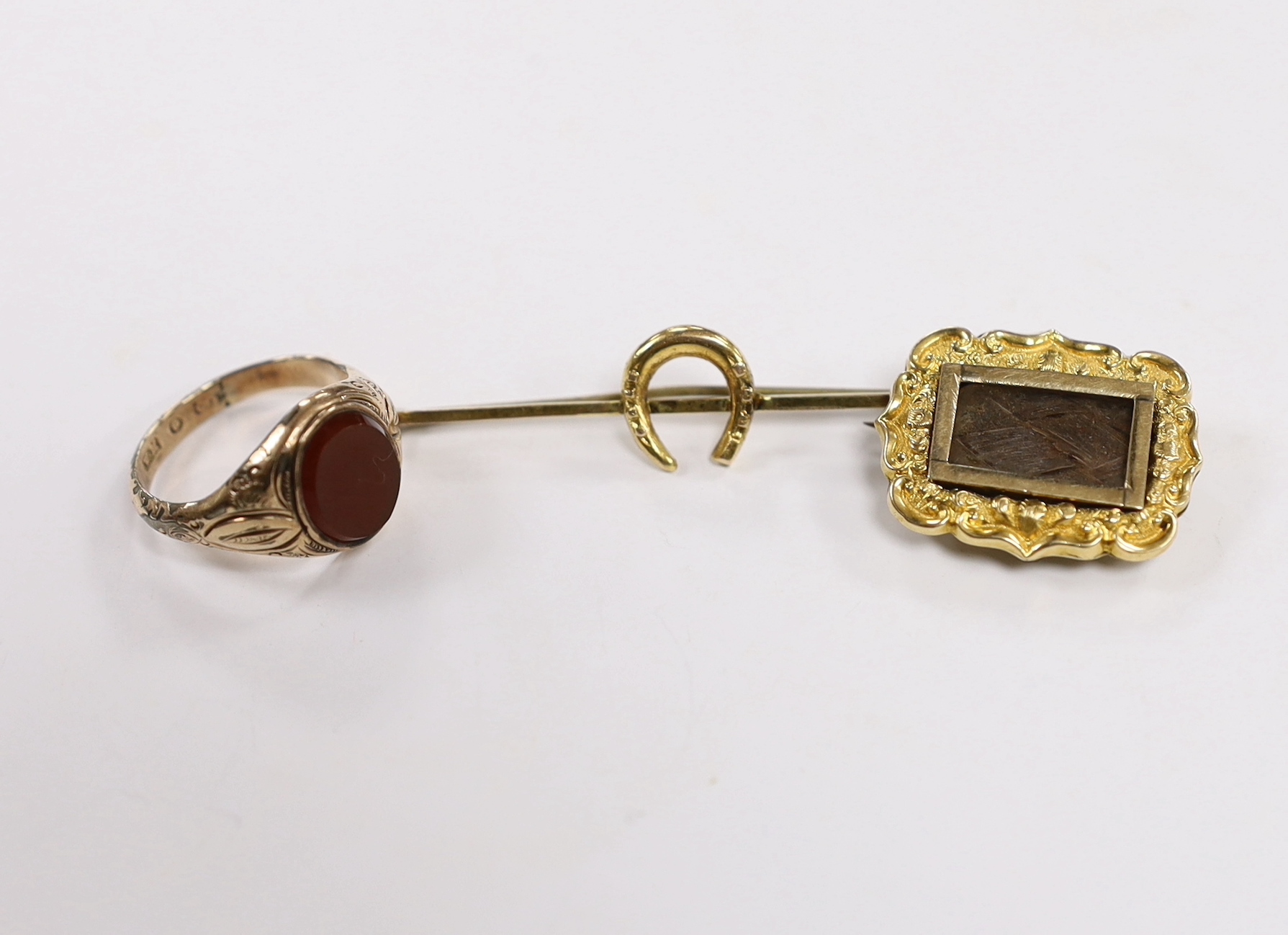 A Victorian 9ct and carnelian set signet ring, size L, an early Victorian yellow metal and plaited hair set mourning brooch, dated 1842 and a 9ct horseshoe bar brooch.